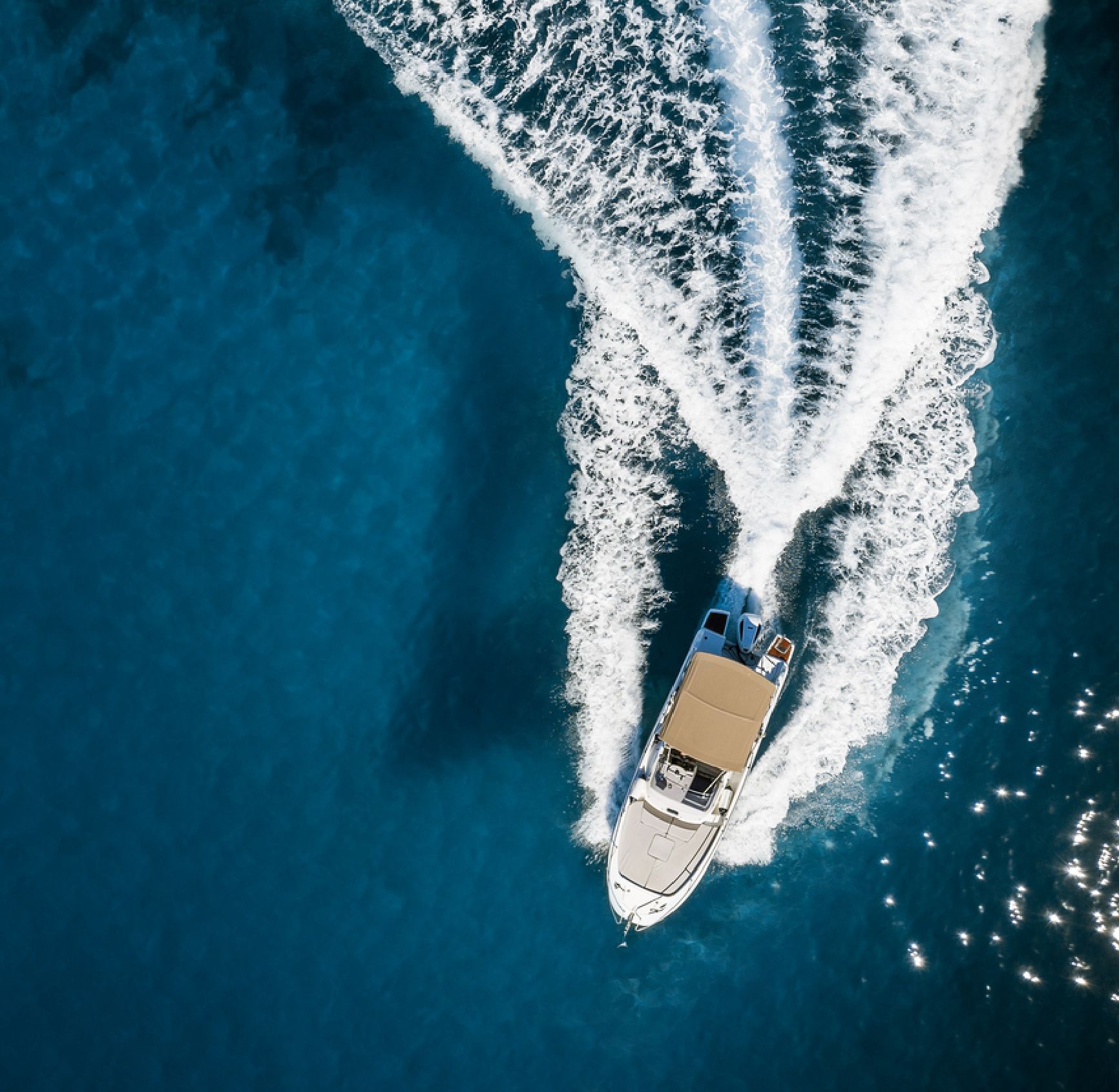 Motorboot von 1ayachtcharter von oben auf dunklem Wasser mit Kielwasser