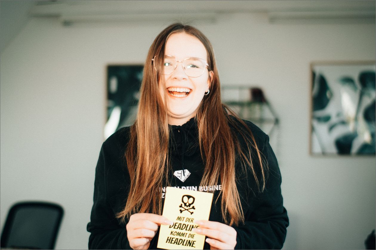 Vanessa hält gelbe Karte mit Text in Büro.