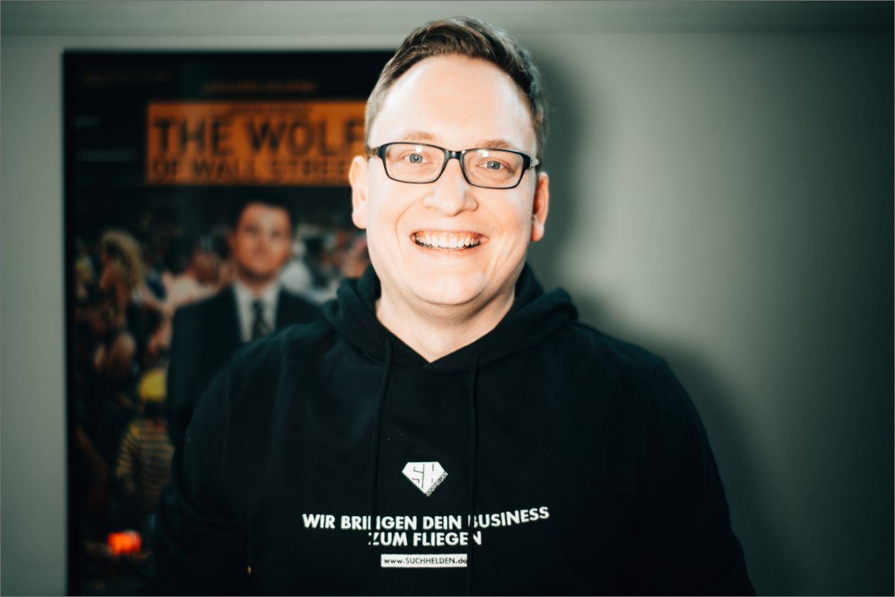 Niklas Meijerink trägt schwarzen Hoodie vor Plakat "The Wolf of Wall Street".