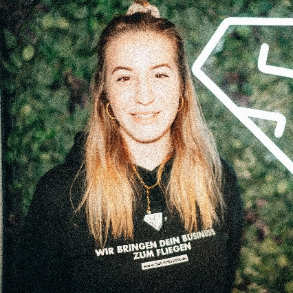 Isabell Jäger trägt schwarzen Hoodie vor grüner Wand mit Suchhelden-Logo