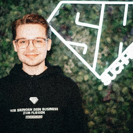 Patrick Tschiedel steht vor einer grünen Wand mit Suchhelden-Logo.